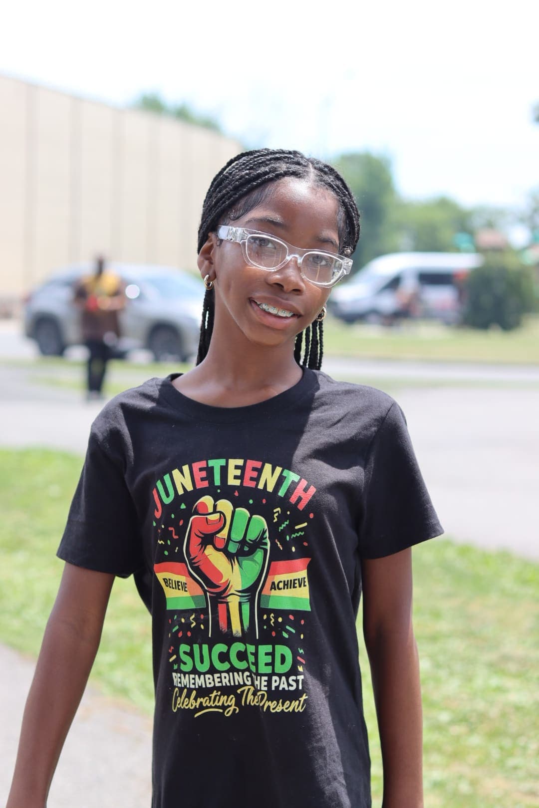 A smiling student wearing a Juneteenth 'Believe, Achieve, Succeed' shirt