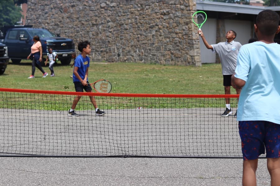 Kids rallying across a portable net on an outdoor court