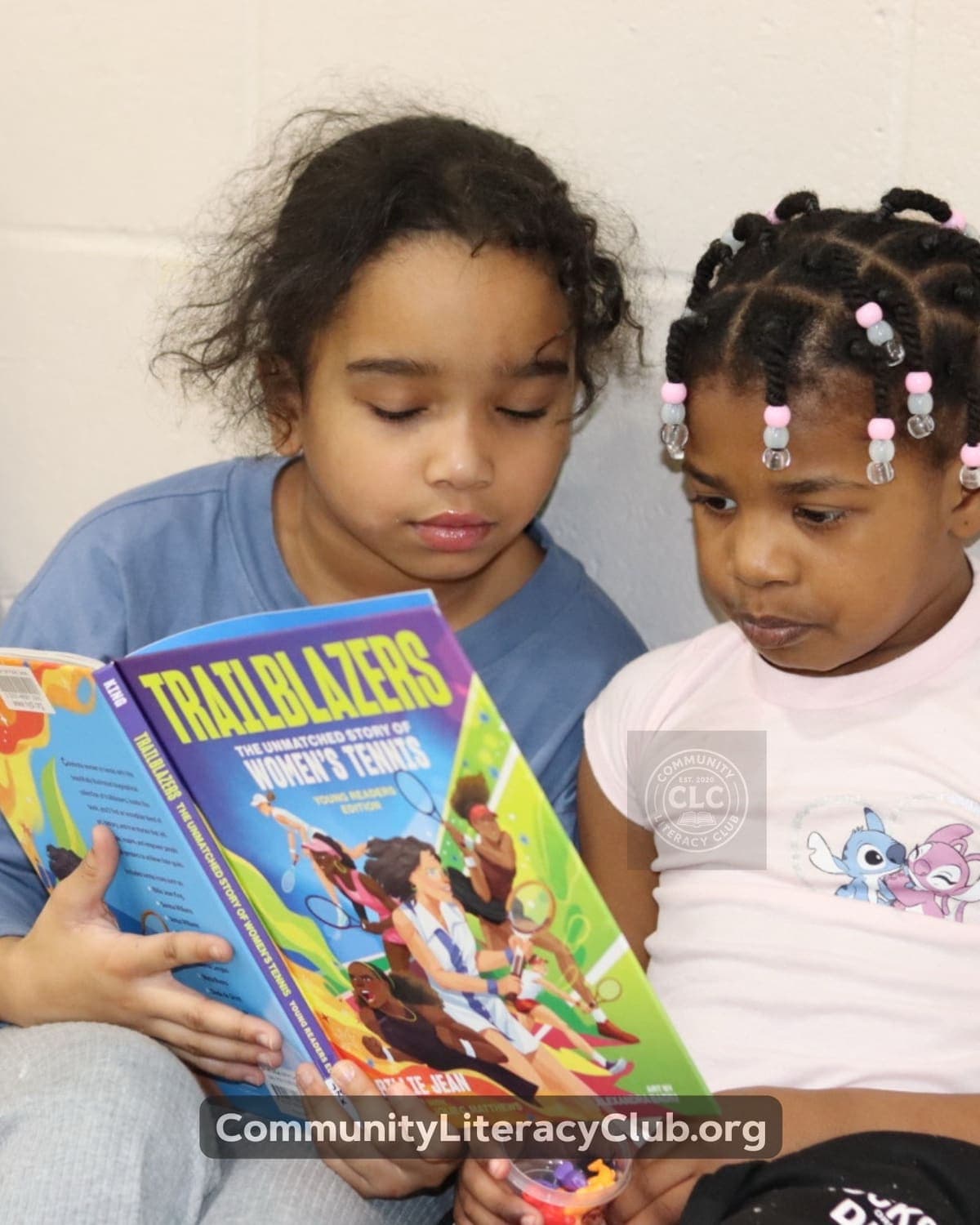 Two young girls reading Trailblazers: The Unmatched Story of Women's Tennis